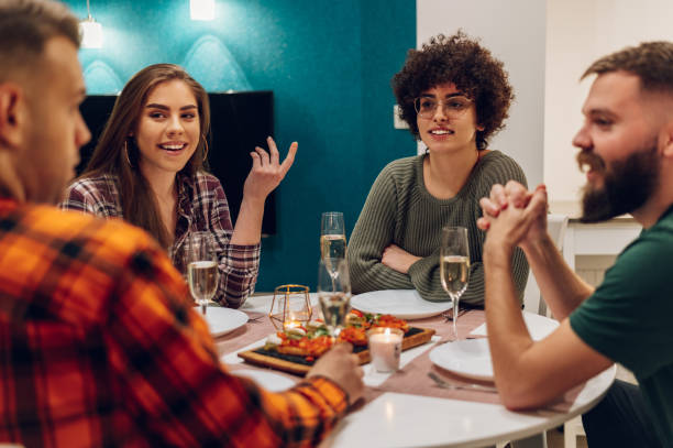 istock Group of friends enjoying dinner while sitting at the kitchen table together 1390145958
