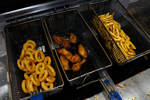 deep fried snack foods in a fat frying basket, french fries, onion rings and wings etc