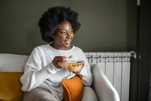 Happy woman eating cereals for breakfast at home stock photo