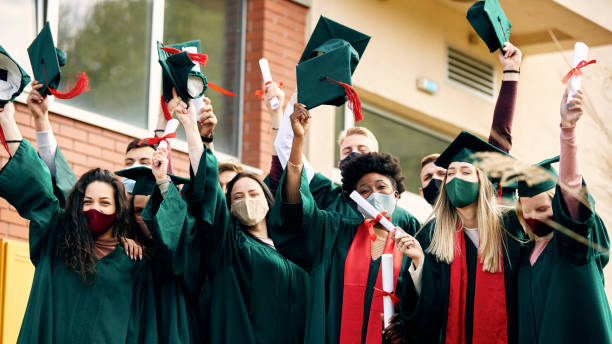 istock Large group of happy students with protective face masks celebrating their graduation. 1390147638