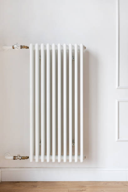 Large white heating radiator with individual adjustment hanging on wall Vertical view of large white heating radiator hanging on wall in modern apartment. Comfortable house with individual adjusted and climate control system. Heat supply and household equipment concept new big tube stock pictures, royalty-free photos & images