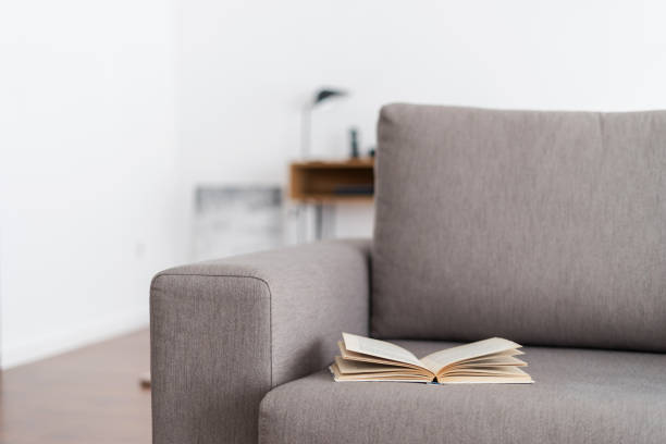 istock Opened paper book in hardcover lying on grey couch 1390149037