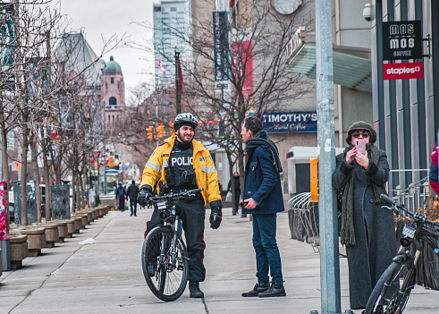 Toronto, Canada - 01 04 2020: Toronto Police bicycle patrol officer talking with a man on University Avenue in Downtown Toronto.
