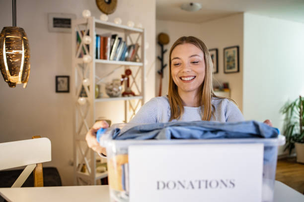 istock Cheerful young woman donating her used clothes 1390153128