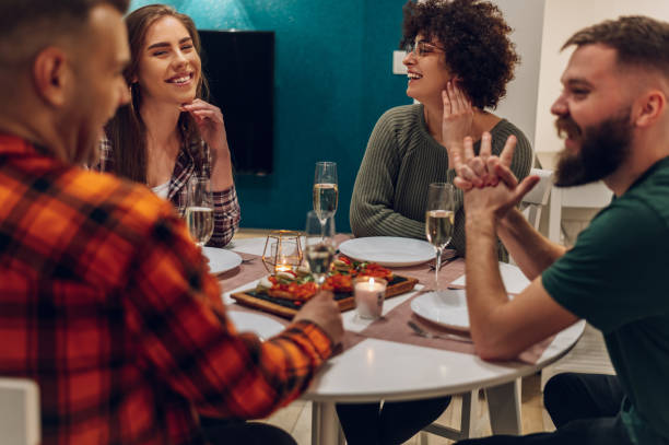 istock Group of friends enjoying dinner while sitting at the kitchen table together 1390153148
