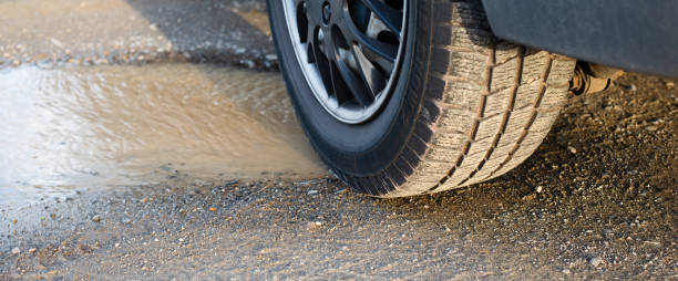 道路の窪み、水たまり以外の車の車輪、雨の後の水穴、ドイツの通りの状況、損傷した高速道路 - water hole ストックフォトと画像