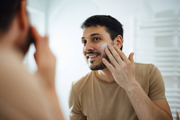 Handsome Man Applying Face Cream in the Bathroom stock photo