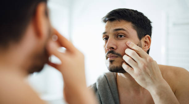 istock Handsome Man Applying Face Cream Under his Eyes in the Bathroom 1390155857