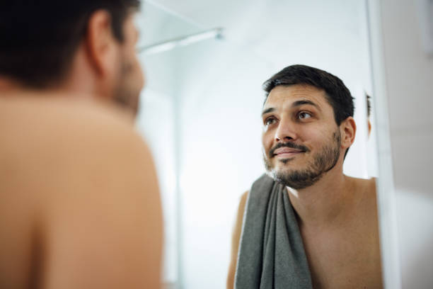 istock Handsome Man Checking his Appearance in a Bathroom Mirror 1390155866