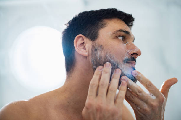 Handsome Man Washing his Face in the Bathroom Close up photo of smiling man using face wash soap in the morning. Skin Preparation stock pictures, royalty-free photos & images