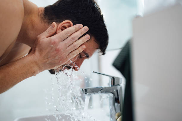 istock Handsome Man Washing his Face in the Bathroom 1390155879