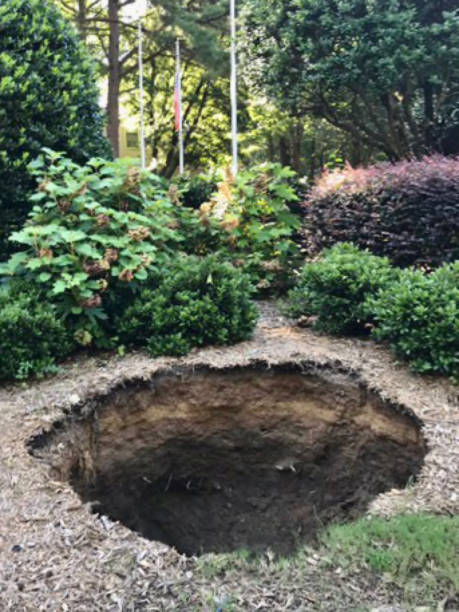 A large sinkhole in the ground A large sinkhole has opened up in the ground sinkhole stock pictures, royalty-free photos & images