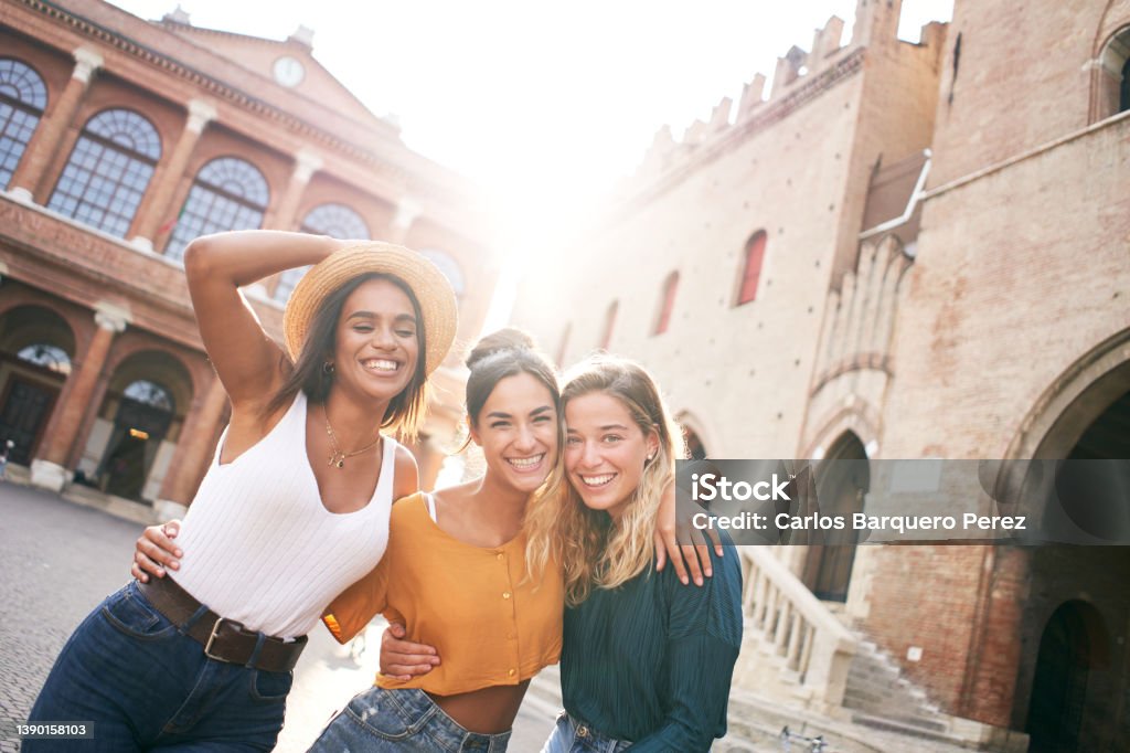 Three happy female friends having fun outdoors in summer vacations at city. Portrait of smiling woman hugging looking at camera together Three happy female friends having fun outdoors in summer vacations at city. Portrait of smiling woman hugging looking at camera together. High quality photo Group Of People Stock Photo