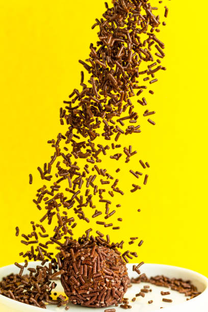 istock Brigadeiro on yellow background with chocolate sprinkles falling on top. 1390159823