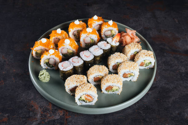 Fresh sushi rolls Set of sushi rolls with cream cheese, rice and salmon on a black board decorated with soy sauce and avocado on a dark wooden background. Japanese cuisine. Food photo background maki sushi stock pictures, royalty-free photos & images