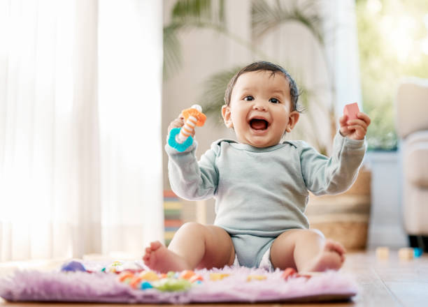 shot of an adorable baby playing with toys at home - baby stockfoto's en -beelden