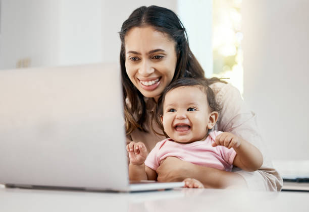 무릎에 아기와 함께 앉아있는 동안 노트북으로 작업하는 여성의 샷 - working mother 뉴스 사진 이미지