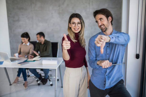 istock Happy young entrepreneurs showing thumb up and thumb down in office. 1390160713