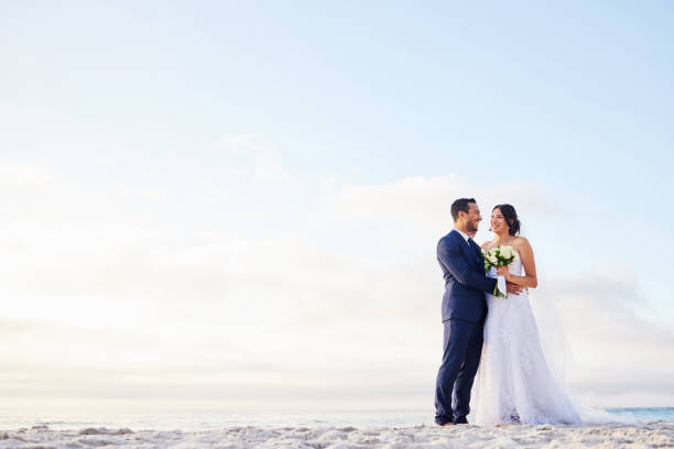 scatto di una giovane coppia sulla spiaggia il giorno del loro matrimonio - wedding beach bride groom foto e immagini stock