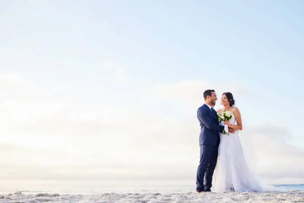 Photo of Shot of a young couple on the beach on their wedding day