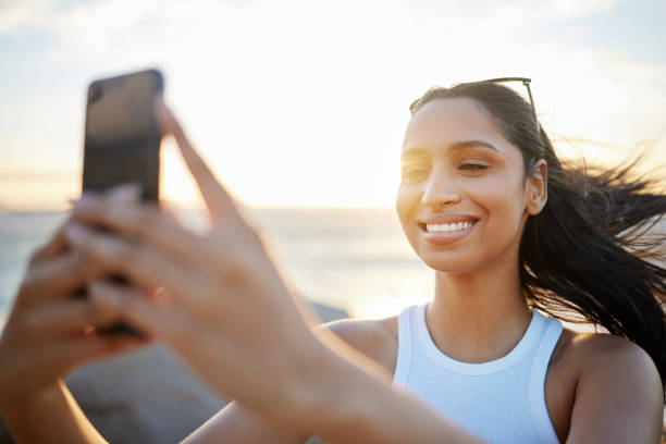 istock Shot of a woman taking a selfie while spending time at the beach 1390160893