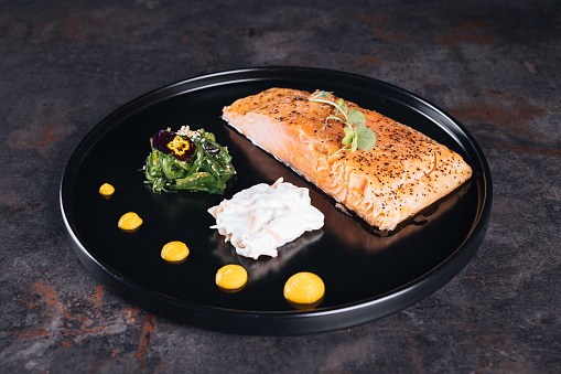 Fried Salmon Fillet Steaks on a wooden board with thyme. Dark wooden background. Top view.