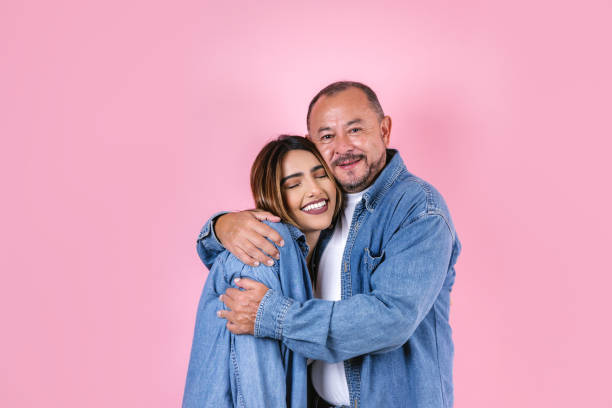 lateinischer vater und tochter in freizeitkleidung in einem kopierraum auf rosa hintergrund in mexiko lateinamerika - senior adult with daughter father stock-fotos und bilder