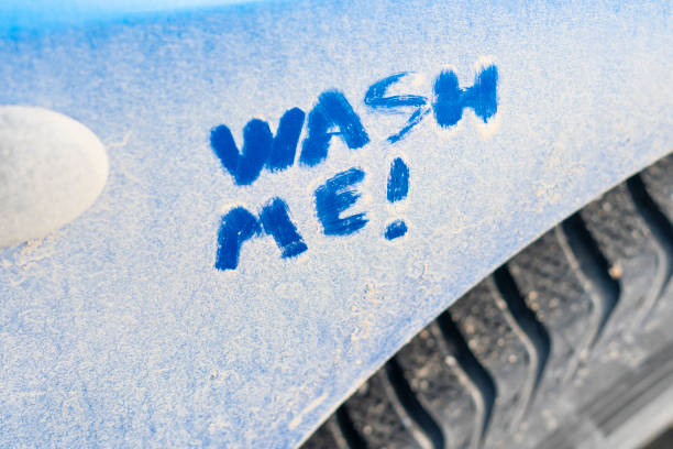 wash me text on the dirty blue car. clean up automobile stock photo