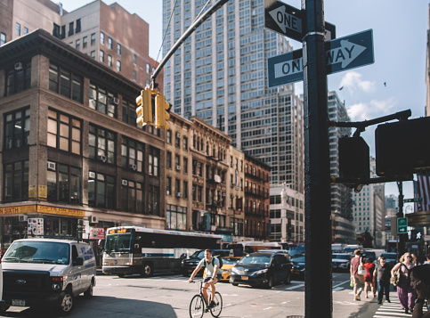 New York, USA - April 16, 2022: People walking on the street in Manhattan, cityscape can be seen in the background.