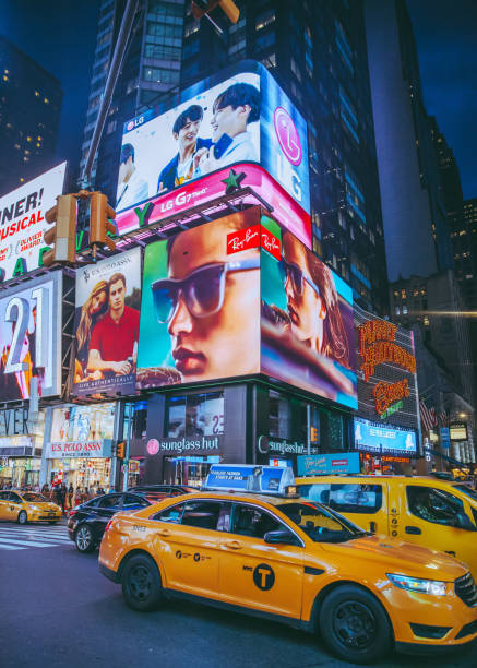 The vibrant and bustling atmosphere of Times Square in New York City at night. The image is filled with towering buildings adorned with bright, colorful advertisements and billboards, creating a dynamic and energetic scene.