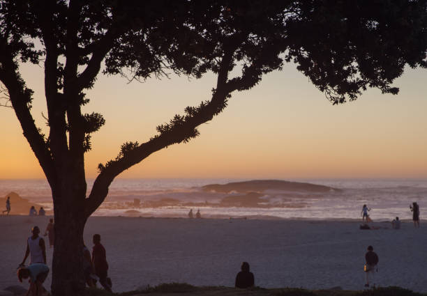 5th May 2022, Cape Town,South Africa: Tourists enjoying the white beach and sun bathing at camps bay in Cape Town,South Africa. Camps Bay is an affluent suburb of Cape Town. Twelve Apostles mountain range in background.