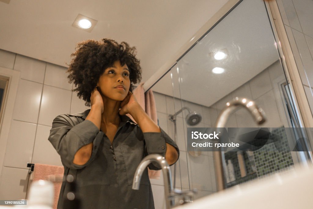 Black girl looks at her mirror in the bathroom Neat Stock Photo