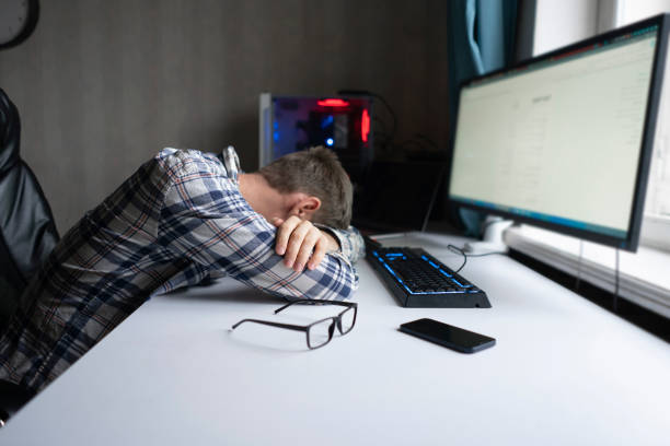 male employee lying on the table, sleep at work, overworking crunch time concept stock photo