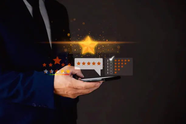 Photo of Close up on customer man hand pressing on smartphone screen with gold five star rating feedback icon and press level excellent rank