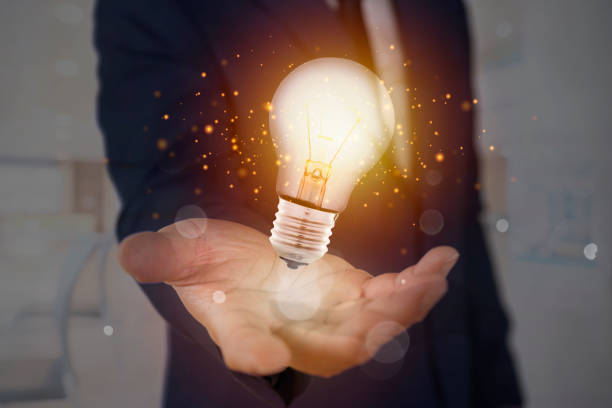 istock Hand of businessman holding illuminated light bulb, idea, innovation 1390188232