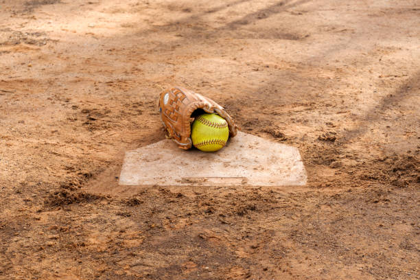 Old softball gloves and old softball balls on the homepage in a softball field. stock photo