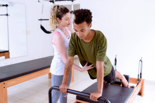 istock Instructor guiding student to perform pilates movement in apparatus. 1390190294