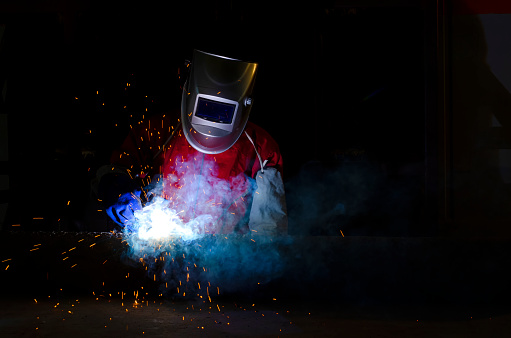Skilled worker crafts steel with precision and dedication. As a shower of sparks flies in all directions, it illuminates a scene of metalworking artistry, a sparks and steel. Craftsman in protective gear operates an angle grinder with unwavering skill and determination. The surface of the metal, which he expertly polishes.