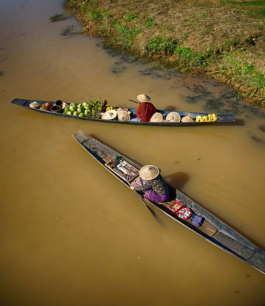 Women sitting on long wooden boat selling souvenirs in Inle Lake, Myanmar