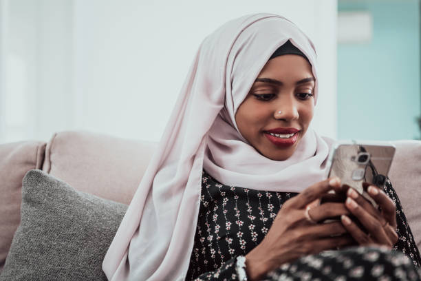 istock African woman using smartphone while sitting on the sofa at home wearing hijab clothes 1390202183