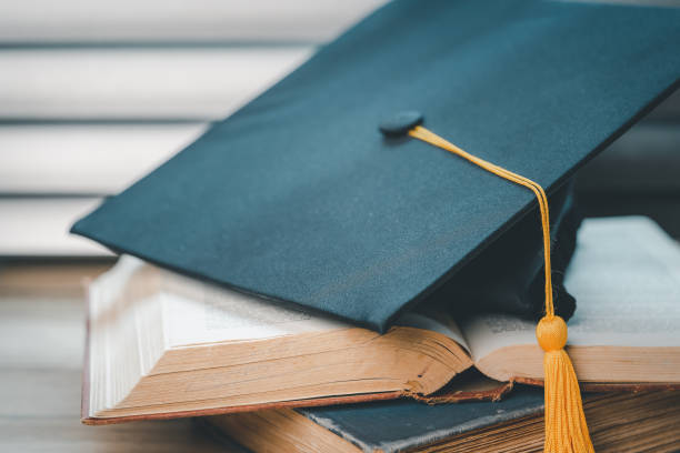 istock single black graduate cap on old books on the table background 1390207392