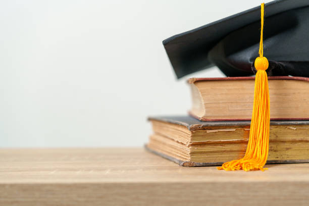 istock single black graduate cap on old books on the table background 1390207476