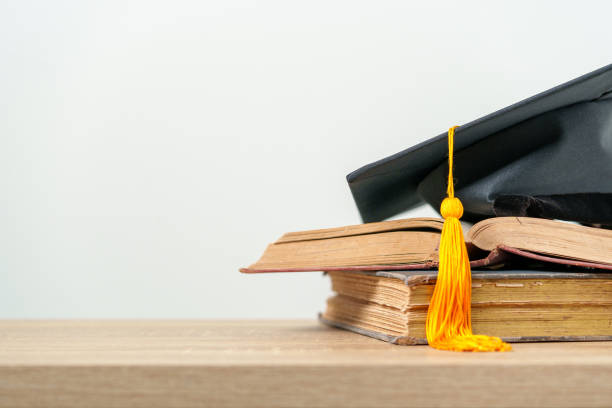 istock single black graduate cap on old books on the table background 1390207479