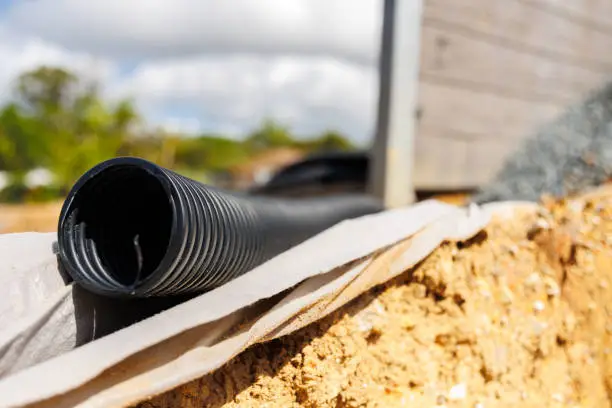 Photo of Drainage pipes behind concrete sleeper retaining wall - shallow depth of field