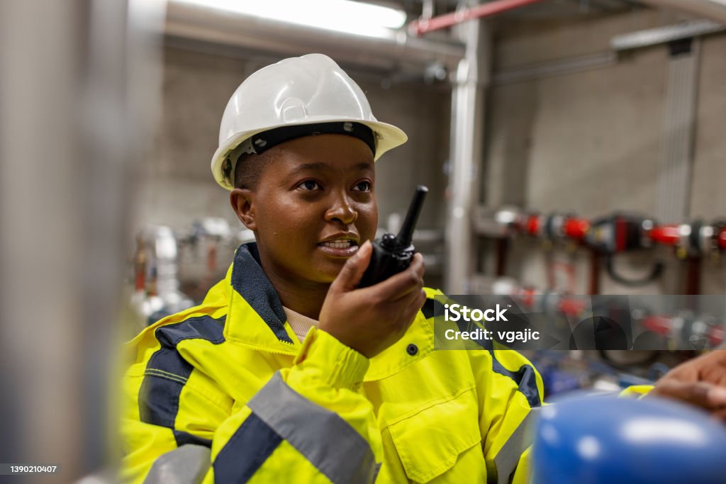 Female Worker Using Walkie Talkie To Communicate Female worker using walkie talkie to communicate. Maintenance Engineer Stock Photo