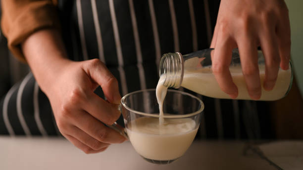 istock Female pouring milk into a glass from a bottle. 1390212920