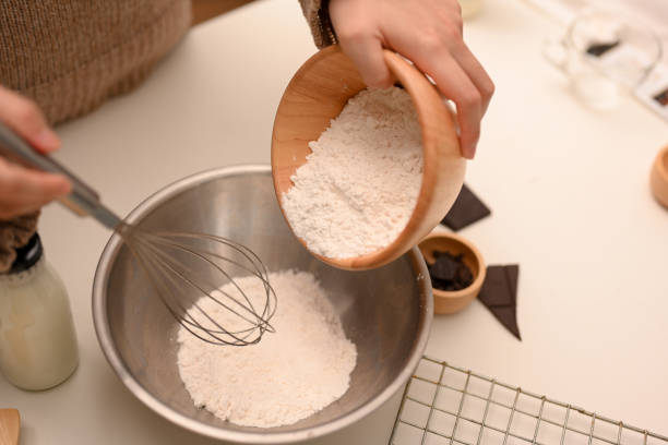 chef sirviendo una taza de harina en un tazón para mezclar. concepto de galletas para hornear. - chocolate chip cookie bakery chocolate homemade fotografías e imágenes de stock