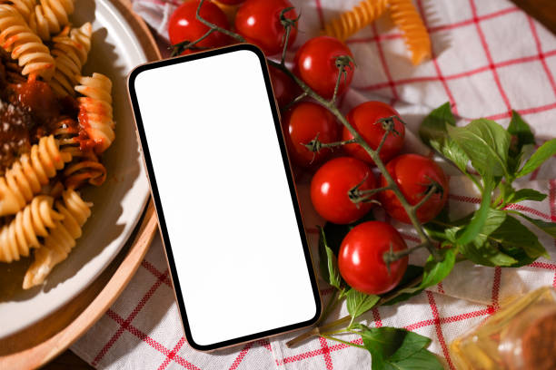 istock Smartphone white screen mockup is on a dining table with a plate of pasta 1390213706