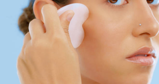 istock Studio shot of a beautiful young woman using a gua sha tool on her face 1390215011