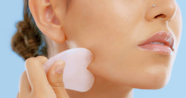 Studio shot of a beautiful young woman using a gua sha tool on her face